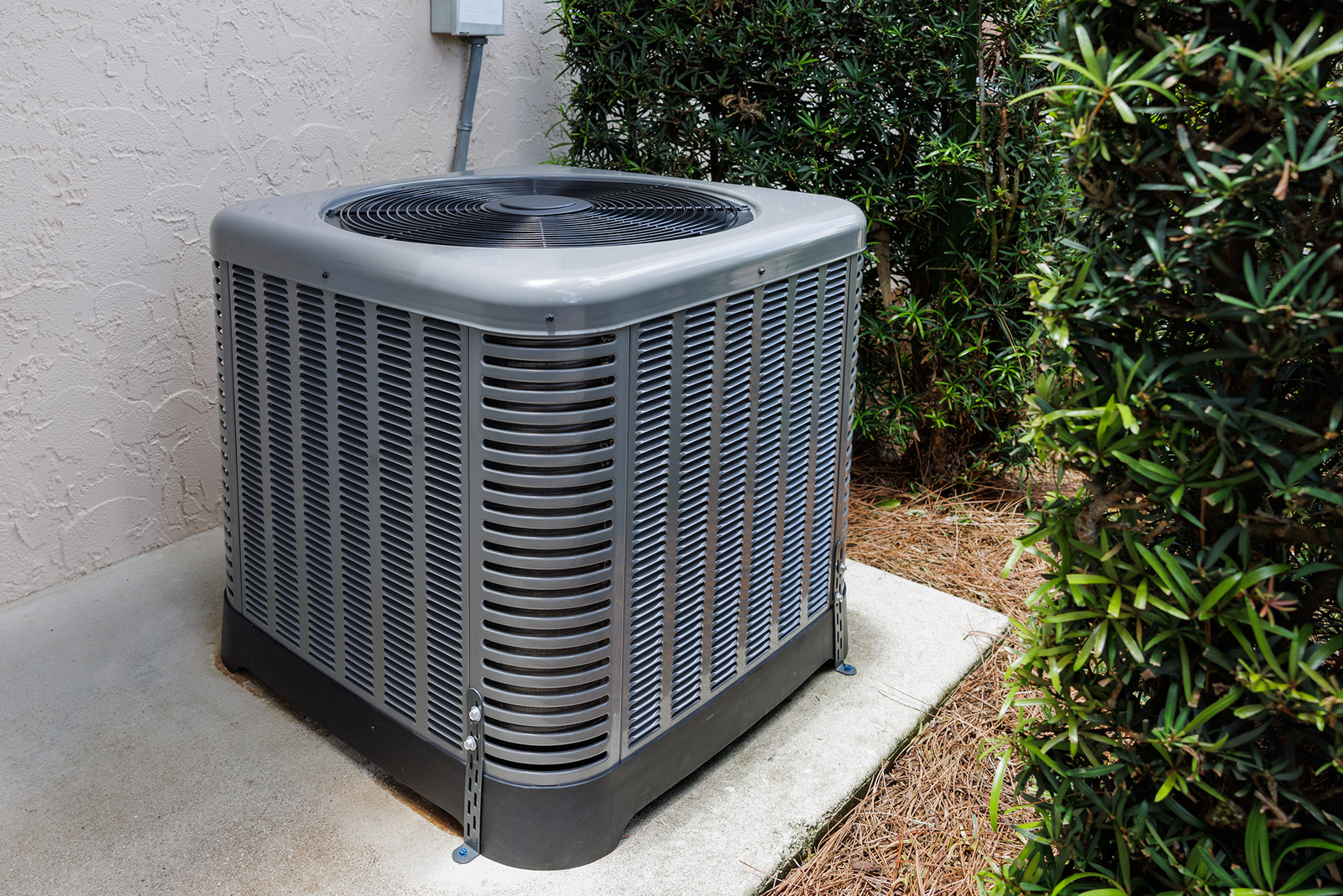 Modern HVAC air conditioner unit on concrete slab outside of house